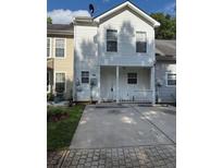 Two-story home features white siding, porch with white railings, and a concrete driveway on a partly cloudy day at 6550 Wellington Chase Ct, Lithonia, GA 30058