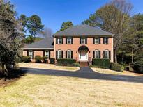 Charming brick home featuring a well-manicured lawn and a long driveway, surrounded by mature trees at 938 Lost Valley Drive Southeast Se Dr, Conyers, GA 30094
