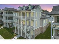 View of three story home featuring double balconies and brick accents on the ground level at 1294 Six Sisters St, Dacula, GA 30019