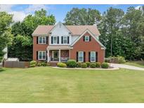 Beautiful two-story brick home with a well-manicured lawn and mature trees at 1975 Fairway Close Ter, Lawrenceville, GA 30043