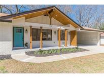 Charming brick home featuring a welcoming porch with wooden columns and a lovely turquoise front door at 442 Mountain Park Trl, Stone Mountain, GA 30087