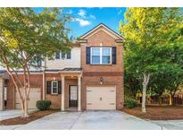 Two-story townhome with a brick facade, attached garage, and small front porch at 2735 Sudbury Trce, Norcross, GA 30071