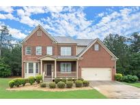Charming brick two-story home featuring a well-manicured lawn and attached two car garage at 1709 Grove Se Ct, Conyers, GA 30013