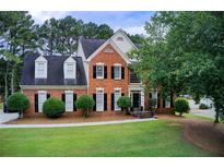 Charming two-story red brick home with a well-manicured lawn and mature trees at 1870 Milfield Cir, Snellville, GA 30078