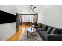 Open living room with hardwood floors, an exposed ceiling, modern lighting, and large windows overlooking the city at 800 Peachtree Ne St # 8607, Atlanta, GA 30308