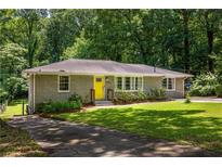 Charming single-story home with a well-manicured lawn and a bright yellow front door at 2041 Trailwood Rd, Decatur, GA 30032