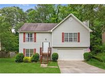 Charming two-story home with gray siding, red shutters, a well-manicured lawn and mature trees at 5519 Princeton Oaks Ln, Sugar Hill, GA 30518