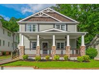 Charming two-story home featuring a welcoming front porch with stone pillars and landscaped yard at 176 Olympic Pl, Decatur, GA 30030