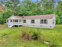Charming single-story home with a white porch, set amidst a lush green lawn and mature trees at 4060 Highway 81, Hampton, GA 30228