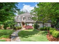 Charming two-story home with manicured lawn, mature trees, and a stone walkway leading to the front door at 5140 Long Island Nw Dr, Sandy Springs, GA 30327
