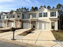 Inviting exterior view of three townhomes, showcasing neutral colors, front-entry garages, and well-manicured landscaping at 3341 Sable Elm Ct, Atlanta, GA 30349