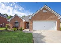 Charming one-story brick home featuring a manicured lawn and two-car garage at 3946 Village Crossing Ln, Ellenwood, GA 30294