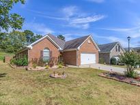 Charming single-story brick home featuring an attached garage and beautifully landscaped front yard at 3946 Village Crossing Ln, Ellenwood, GA 30294