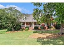 Charming brick home with a well-manicured lawn and inviting front porch with white picket fence detailing at 1112 Sutton Dr, Mcdonough, GA 30252