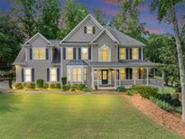 Charming two-story home features a spacious porch, manicured lawn and beautiful, mature trees at 1245 Smokehouse Trl, Cumming, GA 30041