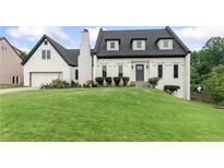 Charming home featuring a well-manicured lawn, black roof, white facade, and an attached garage at 1645 Oakfield Ln, Roswell, GA 30075