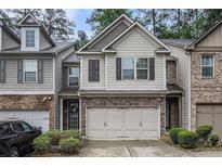 Charming townhome with a two-car garage, neutral siding, stone accents, and manicured landscaping at 2294 Spicy Pine Ln, Lawrenceville, GA 30044