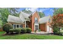 Charming two-story brick home featuring a well-manicured lawn, lush shrubbery, and an attached two-car garage at 1340 Gran Forest Dr, Cumming, GA 30041