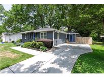 Charming home with gray siding, a blue front door, landscaped yard, and a concrete driveway at 957 Sharon Se Cir, Smyrna, GA 30080