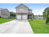 Charming two-story home with gray siding, brick accents, two-car garage, and green lawn at 40 Oakwood Dr, Covington, GA 30016