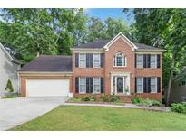 Charming two-story brick home with a well-manicured lawn and attached two-car garage at 3500 Stillwood Dr, Snellville, GA 30039