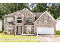 Charming two-story brick home with an attached two-car garage and well-maintained lawn at 1382 Koble Mill Ln, Riverdale, GA 30296