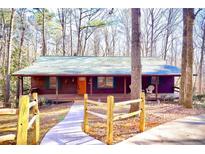 Charming wood cabin with a covered front porch surrounded by a tranquil wooded landscape at 3452 Monica Lane Southwest Sw Ln, Conyers, GA 30094