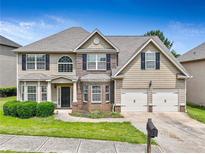 Two-story home with tan siding, brick accents, and attached two-car garage provides suburban charm at 766 Chapman St, Jonesboro, GA 30238