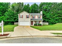 Charming two-story home features a lush green lawn, driveway, and attached garage at 6561 Squire Pl, Douglasville, GA 30135