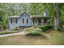 Charming one-story home with a cozy front porch, gray siding, black shutters, and lush landscaping at 3030 Winchester Dr, Cumming, GA 30041