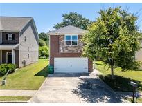 Two-story home with a brick and stone facade, two car garage and a well manicured lawn and mature tree in the front yard at 7268 Loblolly Ln, Morrow, GA 30260