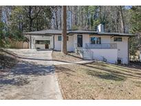 Charming, updated single-story home featuring white painted brick, a covered carport, and a welcoming front porch at 696 Kenilworth Cir, Stone Mountain, GA 30083