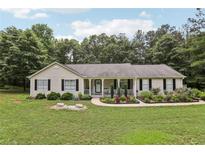 Charming single-story home with inviting front porch and beautifully landscaped front yard surrounded by mature trees at 105 Laney Ct, Mcdonough, GA 30252