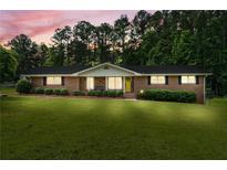 Charming brick home featuring a well-manicured lawn and front-facing shrubs at 8070 Johnson Rd, Palmetto, GA 30268