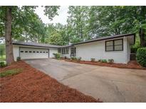 Charming single-story home featuring a brick facade, attached garage, and well-manicured front yard at 7505 Rico Rd, Chattahoochee Hills, GA 30268
