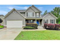 Beautiful two-story home featuring a manicured lawn, charming shutters and a blue front door at 327 Oakland Bay Ct, Loganville, GA 30052