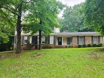 Charming two-story home with brick and siding exterior, set amidst mature trees and a lush green lawn at 2553 Country Club Dr, Conyers, GA 30013