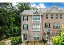 Beautiful brick townhome featuring black shutters, a gray roof and a small front yard with a black metal fence at 2560 Clairebrooke Bnd, Atlanta, GA 30341