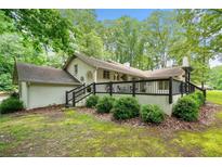 Charming white brick home featuring a spacious deck with black railings and lush, mature landscaping at 3252 Custer Lake Drive Northwest Nw Dr, Marietta, GA 30064