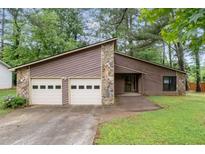 View of a single-story home featuring a 2-car garage, stone accents, and a well-manicured lawn at 9383 Woodknoll Way, Jonesboro, GA 30238