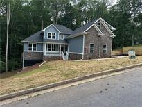 Charming new two-story home featuring stone accents, a welcoming front porch, and professional landscaping at 1119 Plantation Se Dr, Conyers, GA 30094