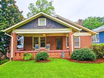 Charming brick home with a cozy front porch featuring rocking chairs and lush green landscaping at 147 Olympic Pl, Decatur, GA 30030