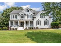 Elegant white brick home featuring a covered front porch, black shutters, and lush green lawn at 735 River Ridge Ln, Suwanee, GA 30024