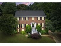 Charming brick two-story home featuring black shutters, manicured landscaping, and a welcoming front entrance at 10645 Tuxford Dr, Alpharetta, GA 30022