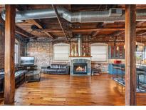 Open-concept living room with exposed brick, hardwood floors, fireplace, and industrial-style ceiling at 490 Marietta St Nw # 307, Atlanta, GA 30313