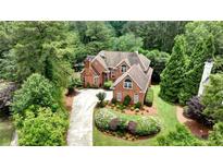 Aerial view of a red brick home with a large yard and mature trees providing a private, secluded feel at 119 Kennemer Ct, Johns Creek, GA 30097