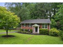 Charming brick home featuring a manicured lawn and mature trees, creating a welcoming curb appeal at 2640 Spring Se Dr, Smyrna, GA 30080