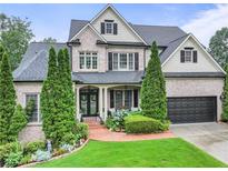 Charming two-story brick home featuring a well-manicured lawn and attached two-car garage at 7060 Summit Ridge Chase, Cumming, GA 30041