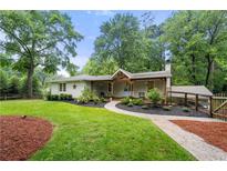 Charming one-story home with a landscaped yard, wooden porch, and a welcoming entrance surrounded by lush greenery at 2020 New Kemp Rd, Marietta, GA 30066