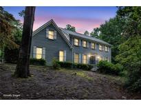 Charming two-story brick home with gray siding, white shutters, and mature landscaping at sunset at 386 Link Rd, Alpharetta, GA 30022